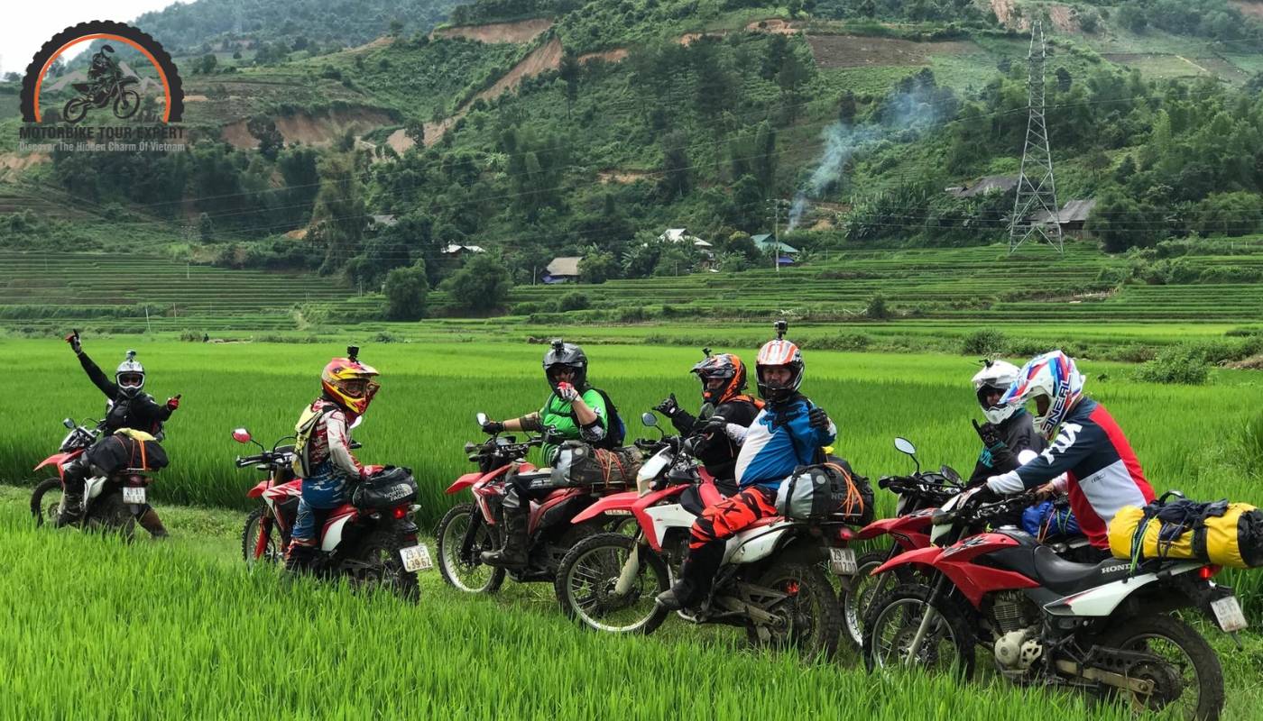 A​​ scenic shot of a motorbike on a winding road through the countryside, with lush rice fields in the background