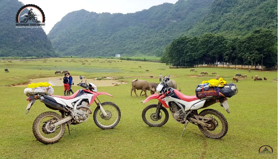 Motorbikes parked in a lush valley surrounded by mountains in Northeast Vietnam.