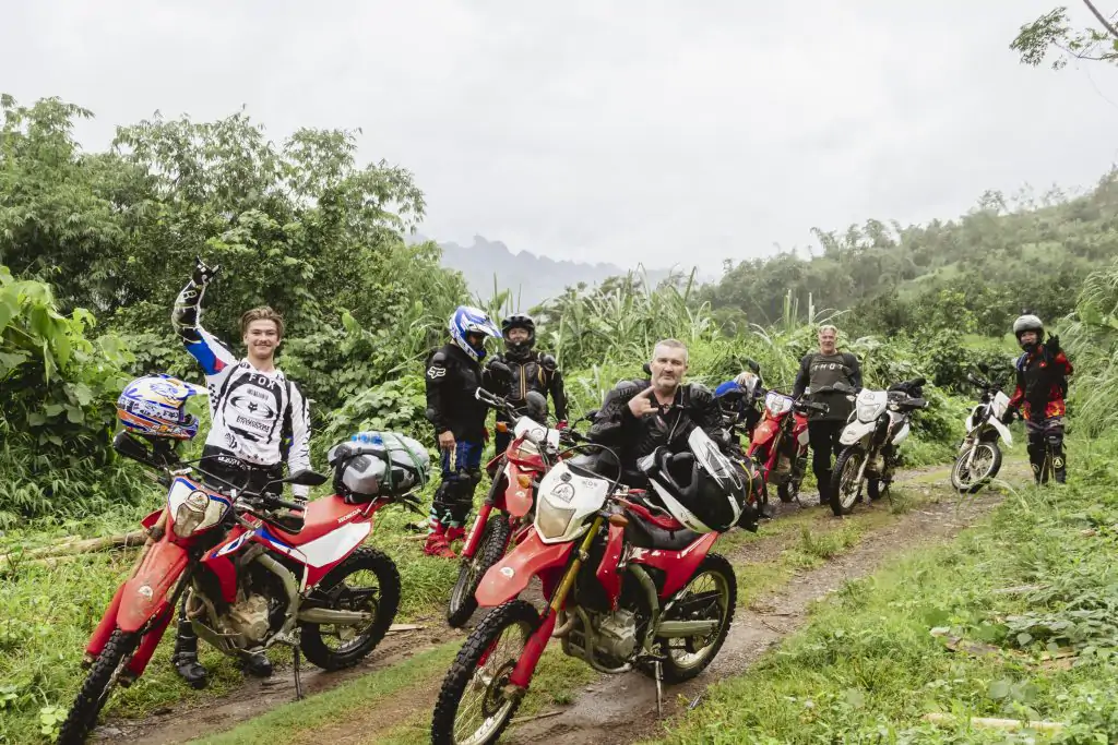 Group of motorcycle tour riders posing on a misty mountain pass in Vietnam to optimize tour budget