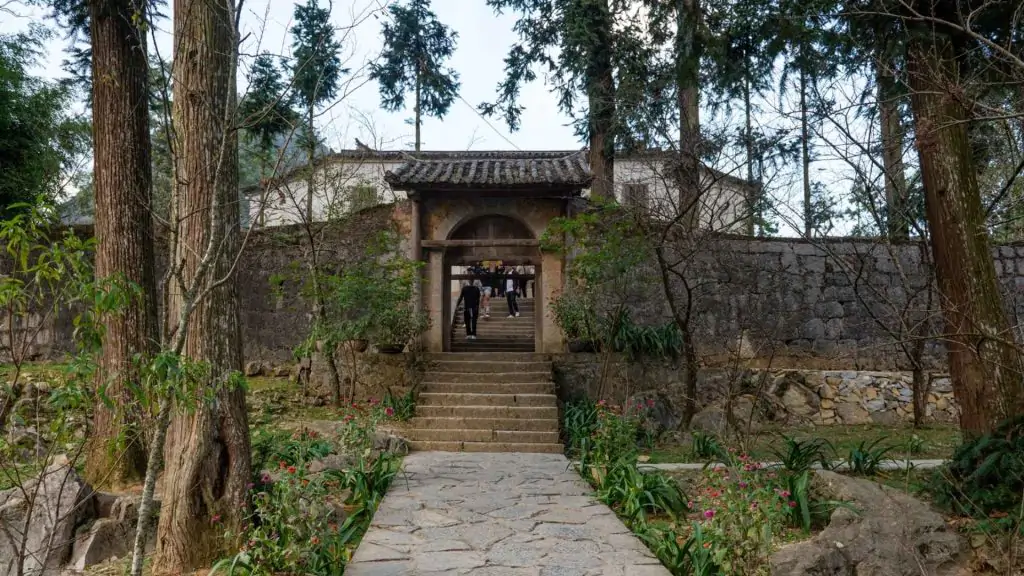 Towering ancient sa moc trees and a majestic stone gate welcome visitors to the Hmong King Palace